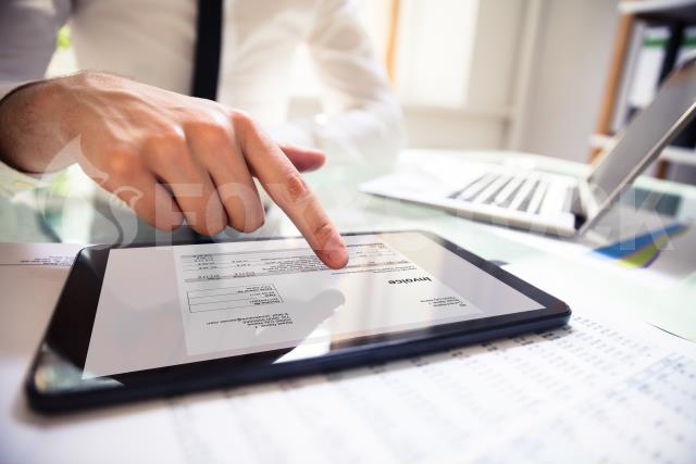 Businessperson Analyzing Invoice On Digital Tablet
