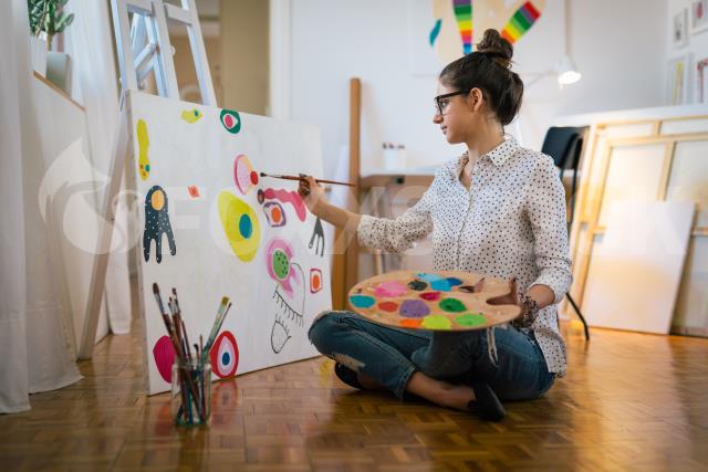 Uma mulher pintando um quadro em uma tela.