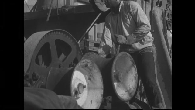 1930s: Man working at machine, gears turning. 