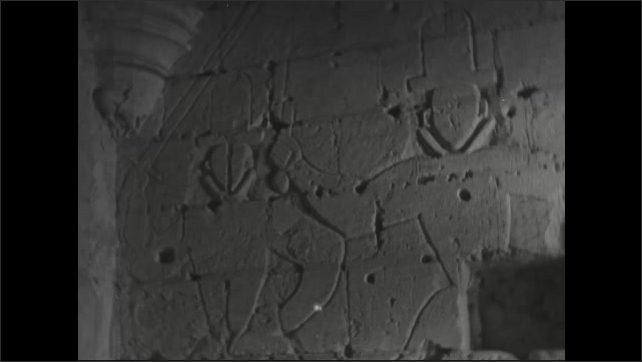 1940s: Castle walls. Stone steps inside castle. Large stone hall inside castle. Engravings on wall.