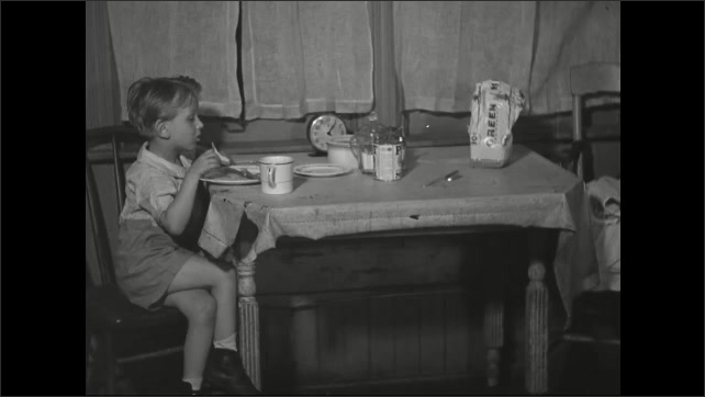 1930s: Boy eating at table, pan to woman. 