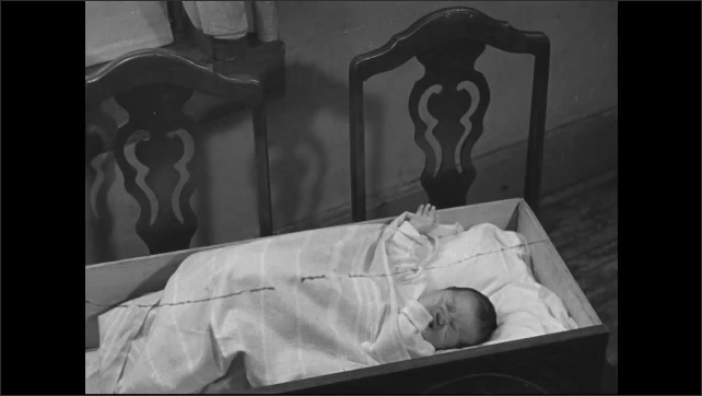 1930s: Baby crying in bassinet, man checks on baby. 