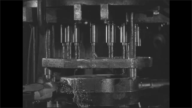 1930s: Rear axle housing is placed in jig, ready to have holes drilled for the differential casing. Drill press is lowered as multiple drills make holes simultaneously.