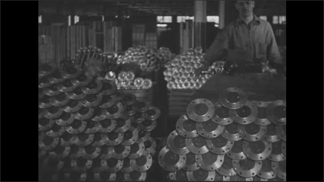 1930s: Bins of finished front axles. Worker with a forklift delivers a new bin of axles. Worker in forklift stops.