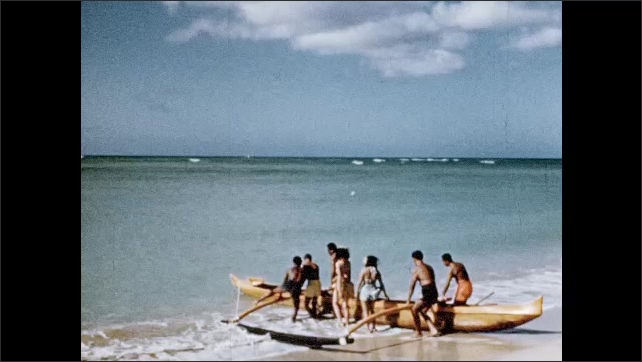 1950s: Waikiki Beach full of people. Royal Hawaiian Hotel. Outrigger canoes launch.