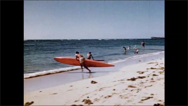 1950s: Surfers ride waves. Surfers carry boards from beach into surf. Outrigger canoe inexpertly launched, then canoe launched by tour guide. 