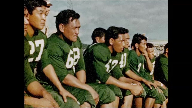 1950s: Campus University of Hawaii. Cheerleaders on field. Football players on field. College football game.