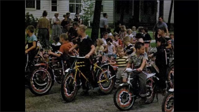 1950s: Kids on bicycles line up on street. Little girl on tricycle.