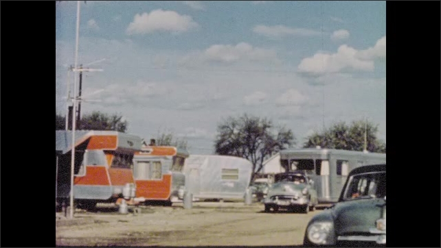 1950s: Man narrates story of arrival in trailer village community as chrome mobile home arrives passes down highway and pulls into village.