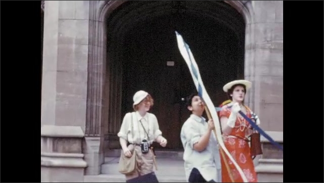 1950s: Bryn Mawr students in humorous costumes perform skit before college building; young woman conducts large group singing