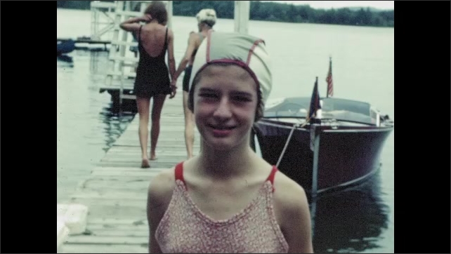 1950s: Girls in bathing cap pose on dock at summer camp; two girls paddle in submerged canoe.