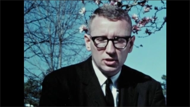 1960s: Bruce Jacob discusses Gideon case outdoors in spring weather. Pink blossom on trees, Man in black suit and glasses. Man talks to camera. Abe Forts talks to camera.