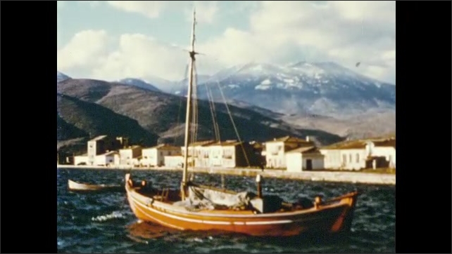 1970s: Mountains and arrows appear on map of Aegean Sea region. Boats sit in harbors near small towns in Greece. Homes sit in mountain valley. Wheat plants wave in breeze.