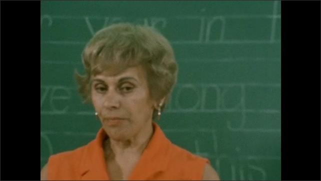 1970s:Woman stands in front of chalkboard, talks.