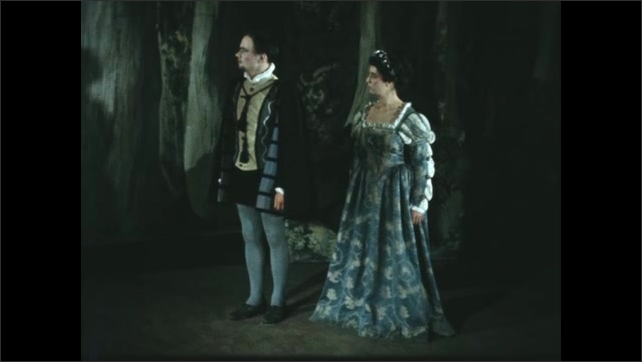 1600s: Man and woman in period costume on stage. Man with clapboard, exits, man in costume talks into camera. 