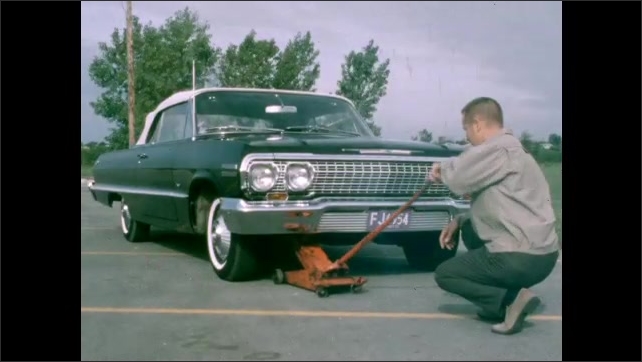 1950s: Green balls roll across surface of light table. Man holds paper placard near car. Man pumps handle on car jack. Man lifts automobile with car jack.