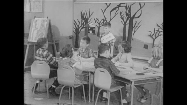 1950s: Boy at his desk getting scissors. Scissors being passed. Teacher at front of class. Surprised safety guide. Children at their desks.