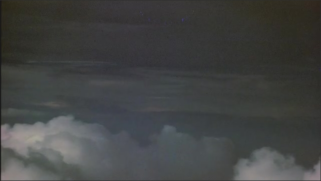 1940s Bikini Atoll: clouds in sky, seen from plane. Atomic bomb detonation, with fireball and condensation rings.