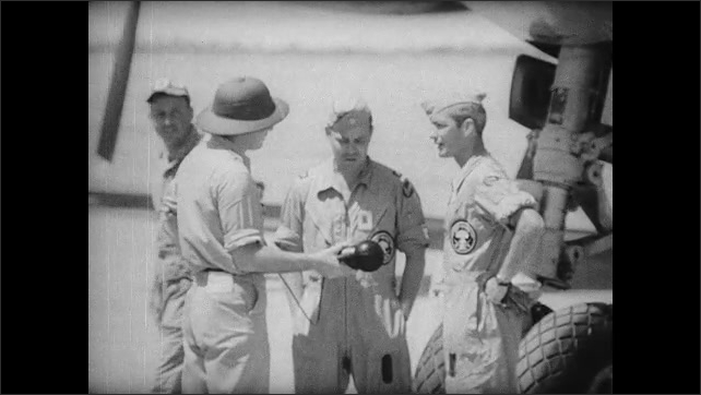 1940s Bikini Atoll: Bomber pilots stand near plane and talk to reporter on runway.