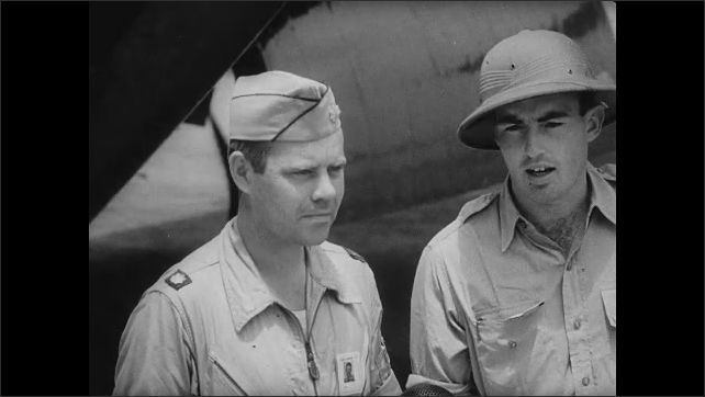 1940s Bikini Atoll: Bomber pilots talks to reporter on runway near plane.