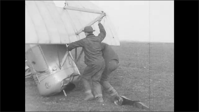 1910s France: Airplane takes off in field.  Man removes propeller from crashed airplane.  Men push airplane back onto ground.  Men carry airplane wing.