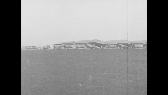 1910s France: Men work on airplane.  Airplanes parked in front of hangar.