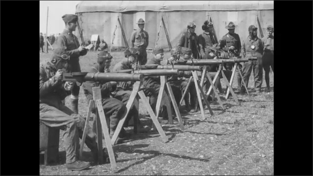 1910s France: Air force base.  Men practice aiming weapons at model planes.