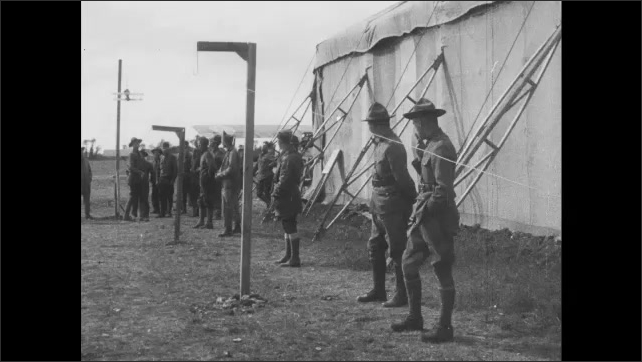 1910s France: Air force base.  Soldiers launch model planes while men practice aiming guns.  Man works on gun.