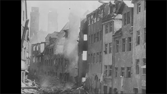 1930s: Flying over destroyed buildings in city. People walk on road by destruction. Road sign on ground. Destroyed buildings. People walking down road. Dead soldiers on ground. Soldiers carry wounded.