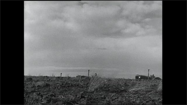 1930s: Field of dirt. Tractors come driving over field.