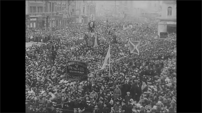1910s: Large crowds of people, walk down street, carry signs. People in courtyard square. Soldiers march in uniforms carrying flags, signs.