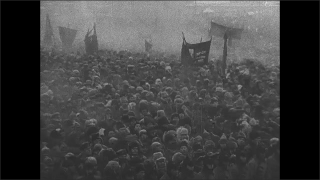 1910s USSR: Lenin's casket is carried through huge crowd of mourners in Red Square in winter cold. Exterior Moscow building in snow. Cannons shoot ceremonial salute. 