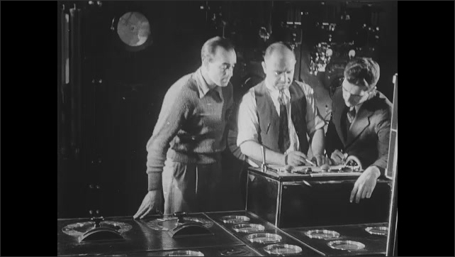 1930s: Gauges on panel. Man operates control panel, pushes lever. Tire on car spins on wheels in wind tunnel test. Men look at results. Scientist in lab. Man adjusts balance weight.