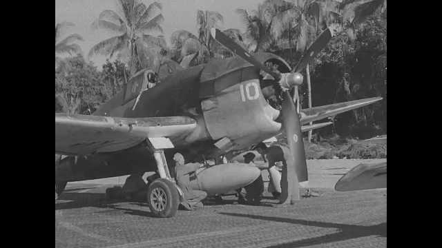 1940s Pacific Islands: Men examine the undercarriage of a propellor plane. Airplane lands on makeshift runway.