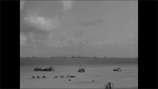 1940s: Boats sit stationary in ocean with fleet of Navy ships on horizon as fallout and debris from nuclear explosion settles in distance.