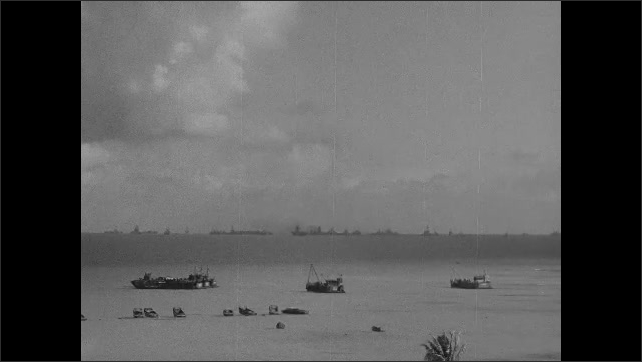 1940s: Boats sit stationary in ocean with fleet of Navy ships on horizon as fallout and debris from nuclear explosion settles in distance.