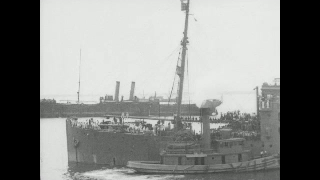 1910s Virginia: Soldiers march into pier warehouse. Intertitle card. Ship pulls away from port.