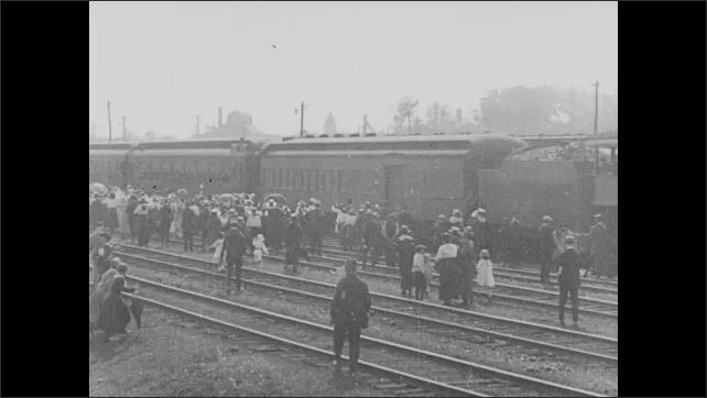 1910s: Countdown. People crowd around train pulling into station.
