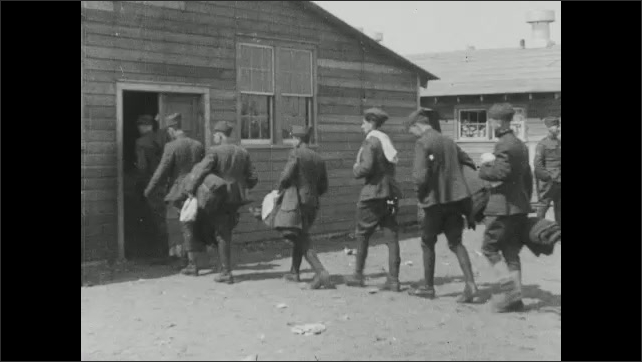 1910s: Soldiers walk around encampment. Soldiers enter bunkhouse. Soldiers operate large machinery.