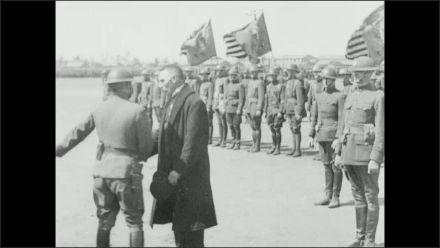 1910s: Men shake hands with soldiers. Soldier pins medal on man's lapel, shakes man's hand. Soldiers stand in formation. Crowd watches. 
