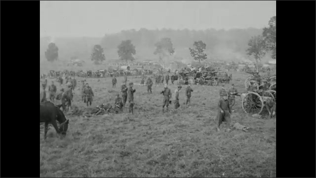 1910s: Men walk around field, horses graze on grass. Men gather supplies from wagons. Men walk down dirt road. 