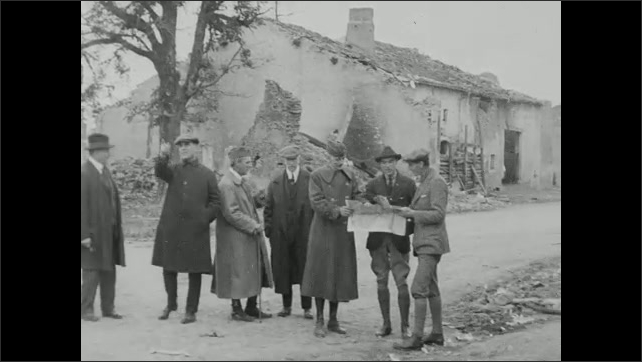 1910s: Men stand in front of ruins of building. Men load into cars. Men stand outside and look at papers. Men look around and point.