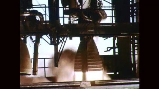 1960s: Rocket engine test fires. Men move rocket engine. Men adjust ...