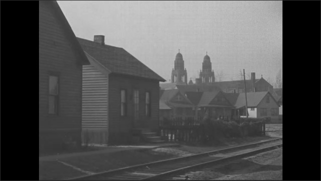1930s: Row of houses in front of railroad tracks. Church building.