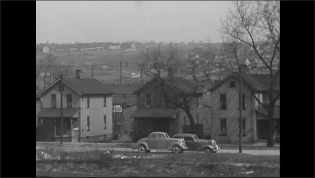 1930s: Houses next to factories, with cars parked in the street. Slate.