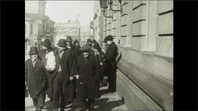 1910s: Evicted men walk from apartment building as police watch. Police officer leads men to makeshift cage.