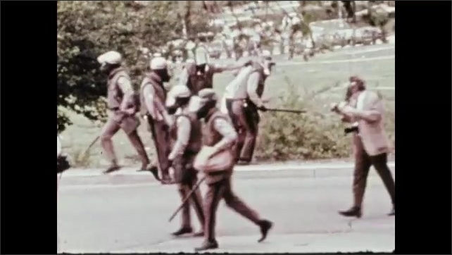 1970s: Police shooting teargas at protestors. Protestor throwing an object. Text over pictures of rioting. Man arrested by large group of police.