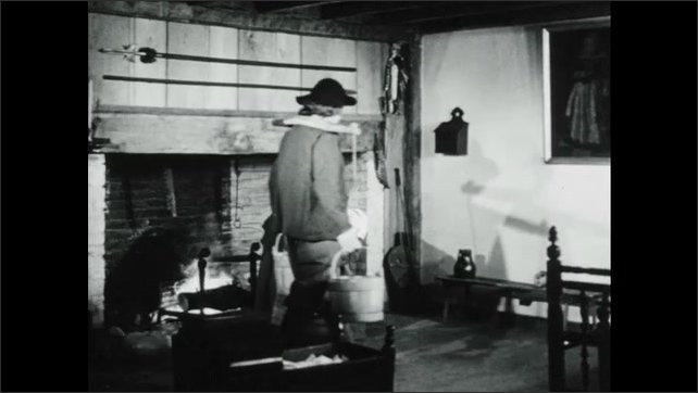 1940s: A wooden two story house on a hill. Woman pulls a three legged pot from the fireplace. Man enters with two buckets on a yoke. Woman spoons out mush to plates held by a girl.