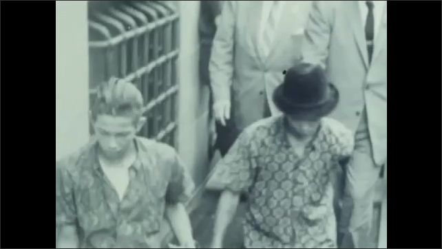 1960s: wealthy defendant arrives at court with umbrella. Poor defendants arrive at court. Photographs of defendants outside court building. 