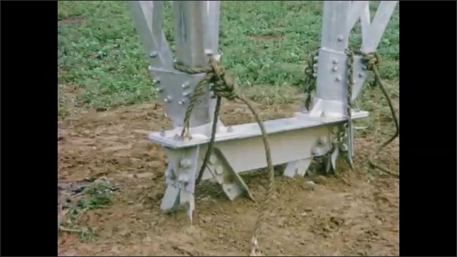 1960s: UNITED STATES: man fixes frame to ground structure. Ropes around ...